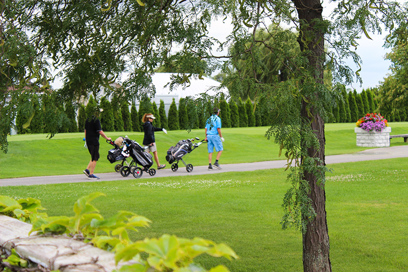 caddies pushing pull carts on a golf course